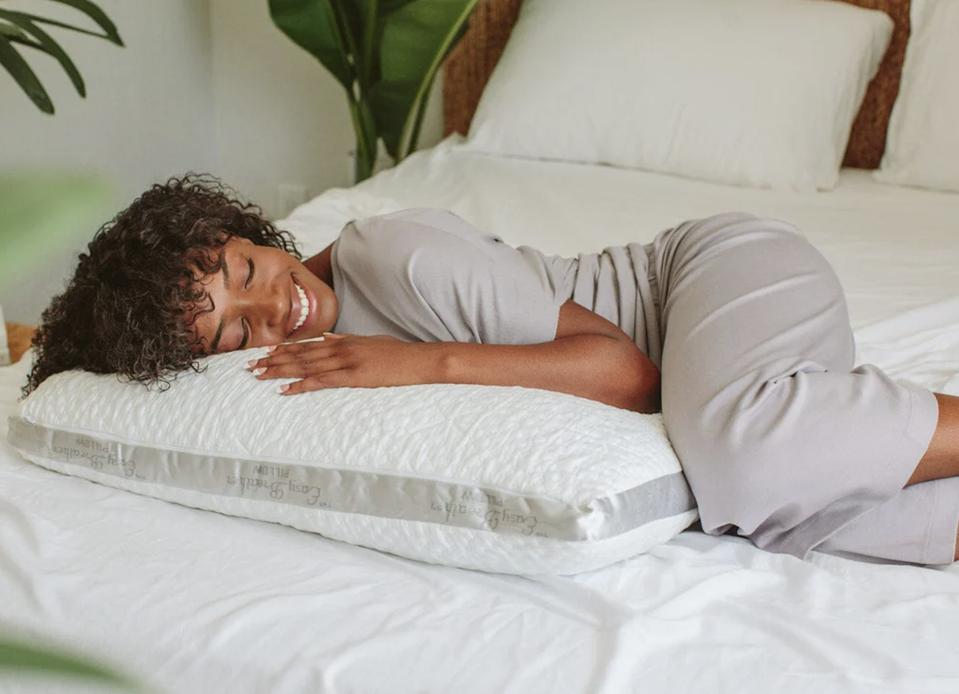 A Black woman smiling while lying on the Nest Bedding Easy Breather on a bed