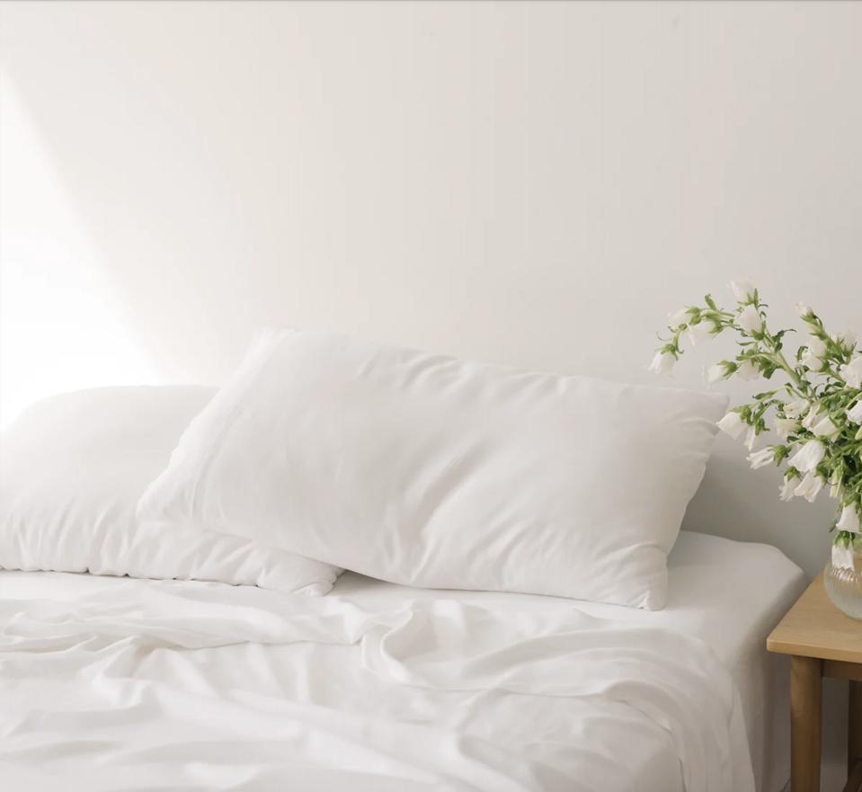 Cozy Earth Bamboo Sheets Sets in white in a white bedroom with flowers on a nightstand. 