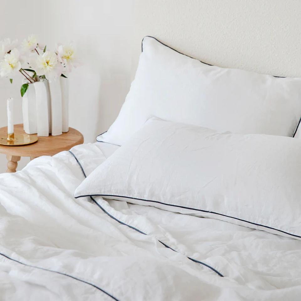 Cultiver Piped Linen Sheet Set in white and navy on a bed.