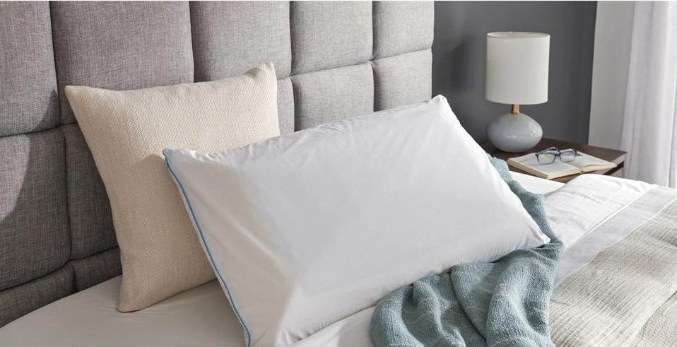 TEMPUR-Cloud Breeze Dual Cooling Pillow on a bed with an upholstered headboard. 