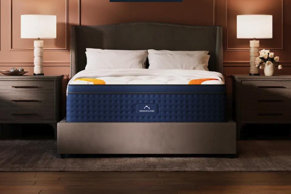 The DreamCloud Premier Rest Hybrid on a upholstered frame in a bedroom.