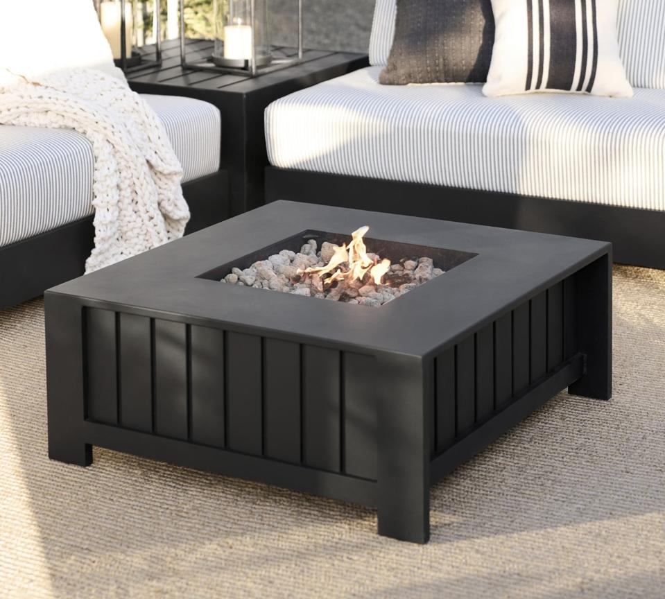 Pottery Barn Malibu Metal Fire Pit Table on a patio surrounded by two outdoor sofas