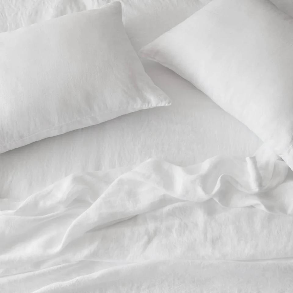 The Citizenry Stonewashed Linen Sheet Set in white next to two pillows