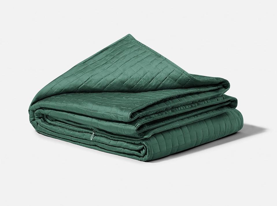 Green Gravity Blanket folded and stacked on a white background.