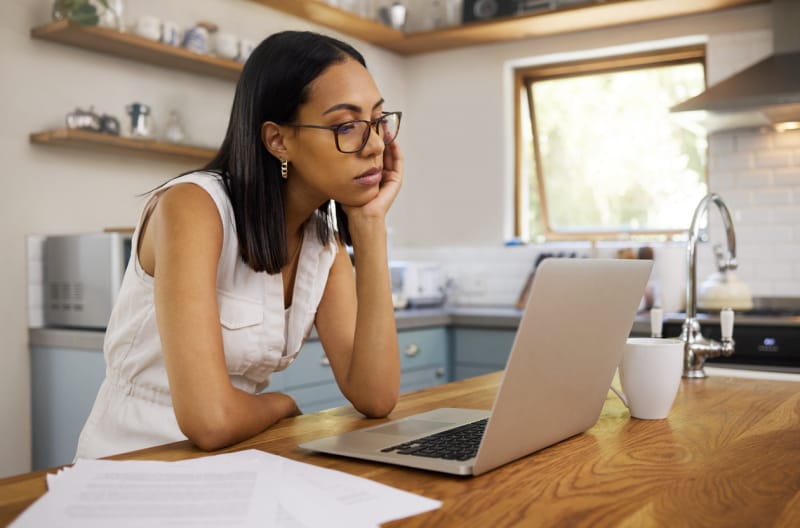 Les 11 plus grosses erreurs que vous pouvez commettre avec votre maison intelligente femme frustrée par une mauvaise connexion internet regardant son ordinateur portable dans la cuisine