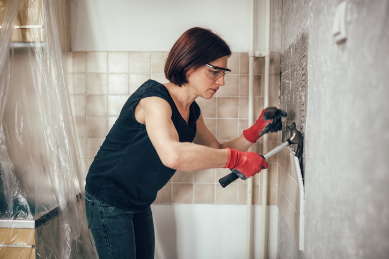 Femme arrachant le carrelage d'une salle de bains