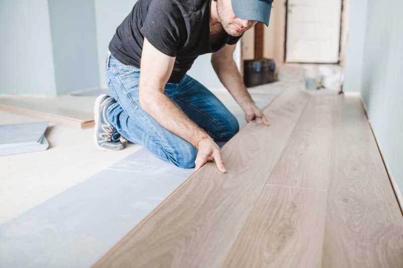 Un ouvrier pose des lames de parquet.