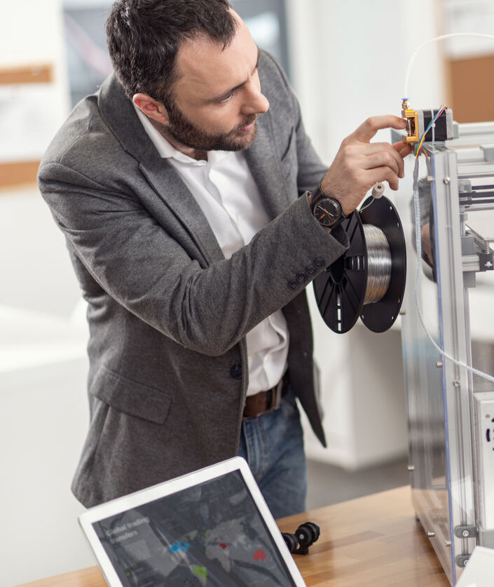 iStock-925925590 opportunités de bénévolat jeune homme remplissant du filament dans des imprimantes 3D