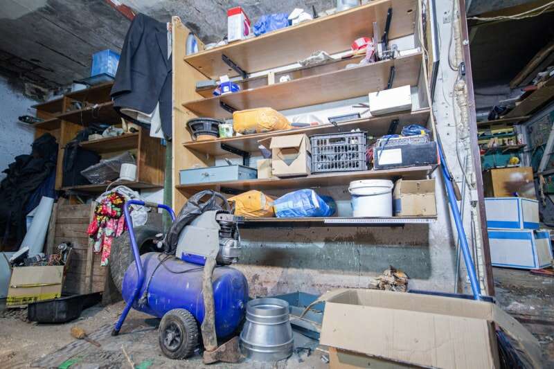 Étagères de garage à domicile avec des produits et des machines poussiéreuses.