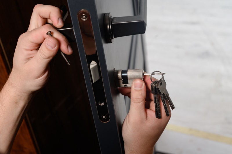 Serrurier installant le noyau de la serrure dans une porte.