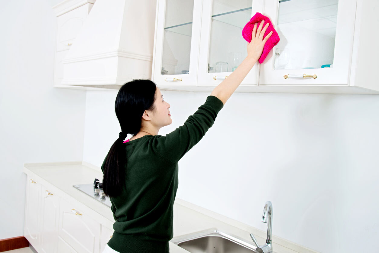 femme asiatique nettoyant les armoires de cuisine