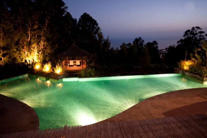 Piscine avec lumières dans l'eau et éclairage dans l'aménagement paysager environnant.