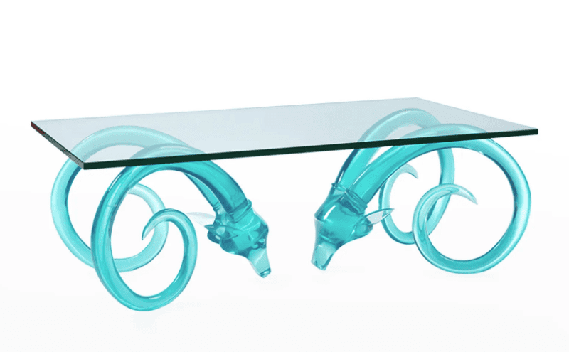 produit table de cocktail avec plateau en verre et base composée de deux têtes de bélier translucides turquoise avec de longues cornes délicates en spirale