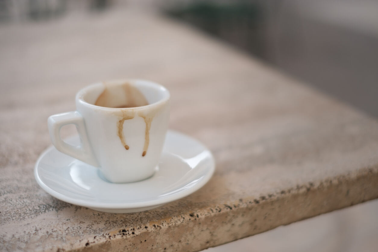 Une tasse à expresso vide et sale sur une table en marbre.