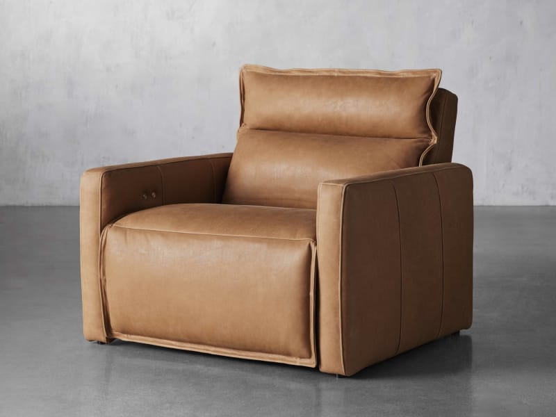 Un fauteuil club Arhaus en cuir marron camel dans une pièce grise