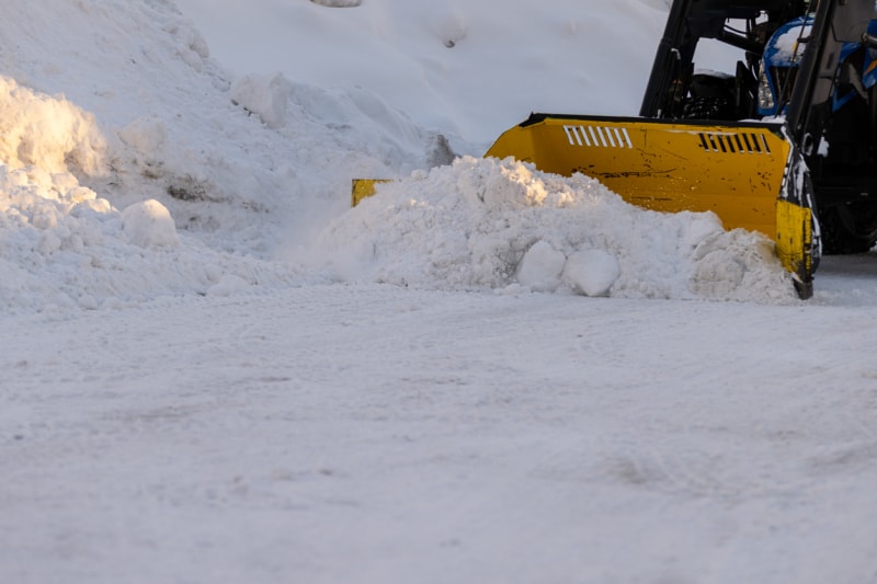 Gros plan d'une souffleuse jaune près d'un banc de neige.