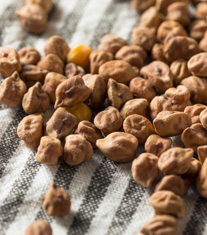 Pois chiches indiens séchant sur une serviette à rayures grises et blanches.