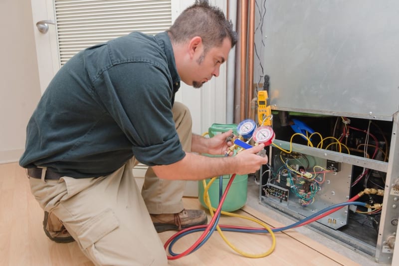 Un ouvrier utilise un outil pour tester le fonctionnement d'une unité HVAC.