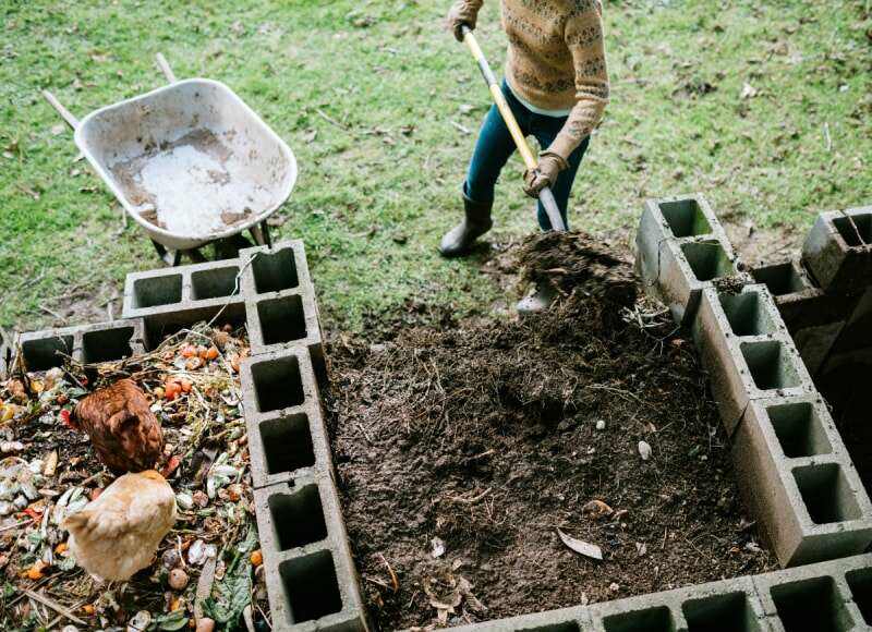 femme-ramassant-du-compost-riche-en-nutriments-dans-une-brouette-image-id1200151530