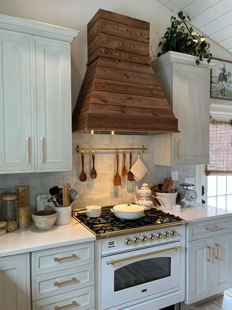 Une hotte de cuisinière en faux bois avec une bordure dorée dans une cuisine sur le thème de la ferme.