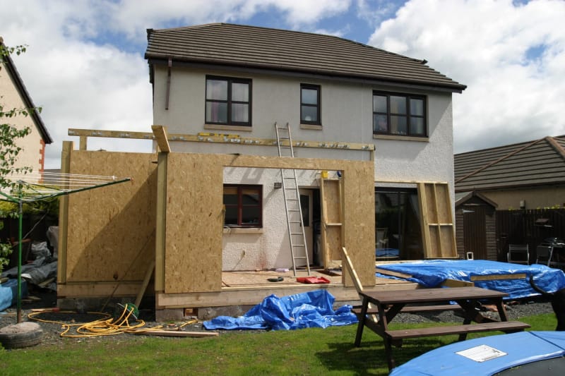 Une extension est en cours de construction à l'arrière d'une maison à deux étages.