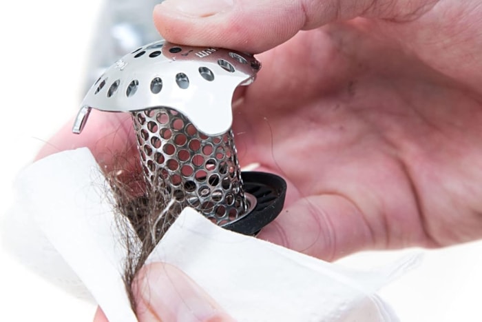 Quelqu'un enlève un récupérateur de cheveux dans un drain de douche rempli de cheveux