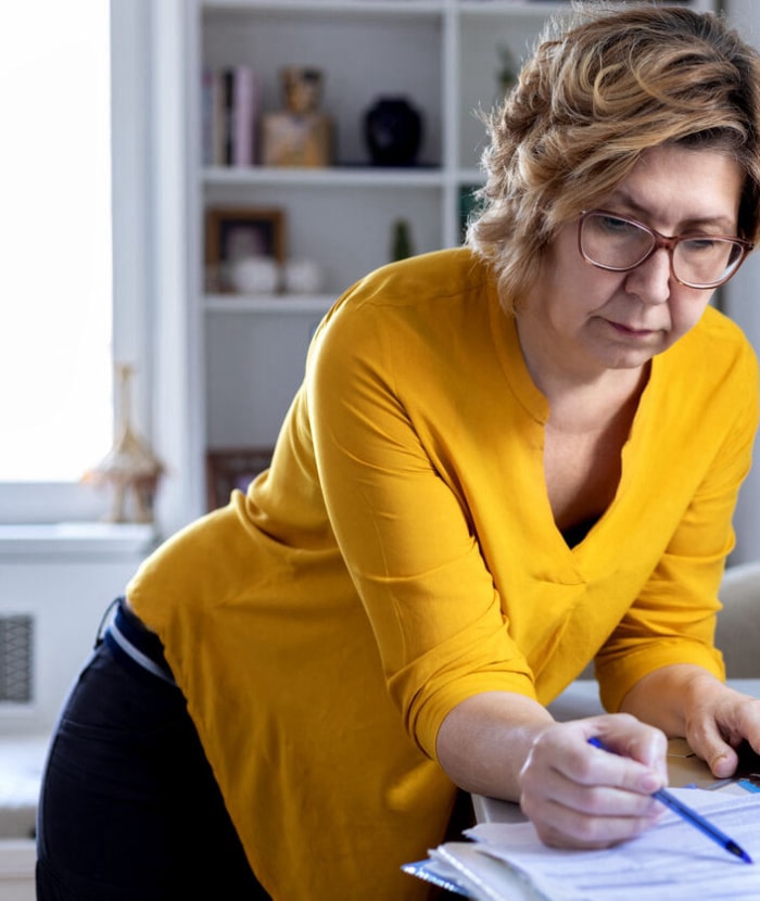 femme mature examinant des applications à côté d'un ordinateur portable