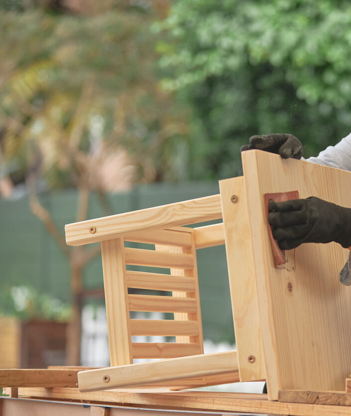 Menuisier ponçant une petite table en bois dans son atelier.