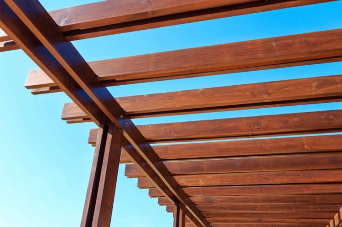 Le ciel est visible entre les poutres en bois du toit d'une pergola.