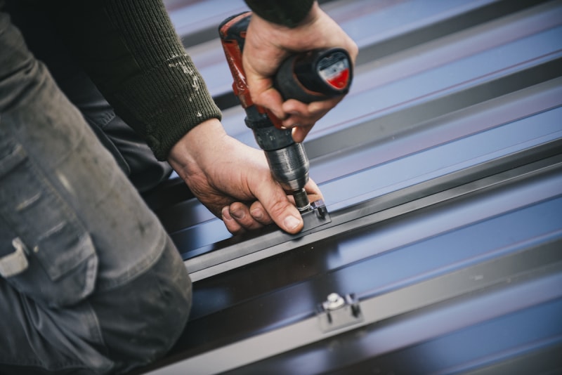 Une personne utilise un outil pour installer une toiture métallique sur une maison.