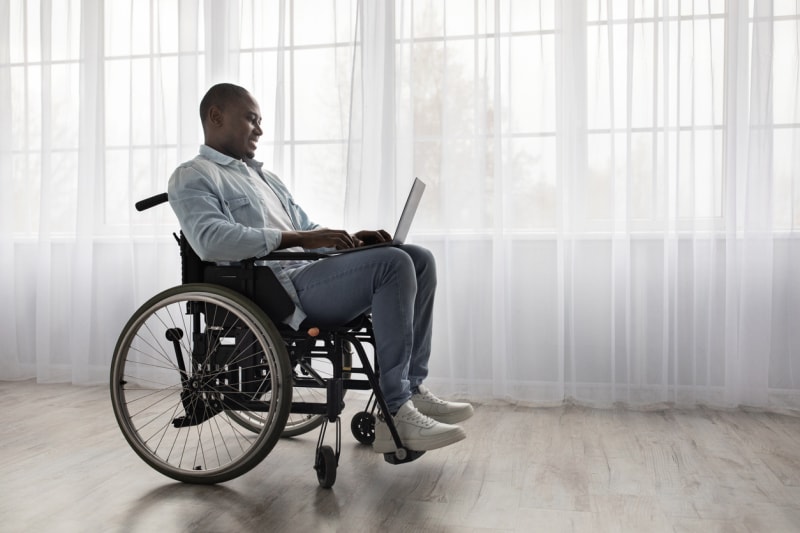 iStock-1322890936 Homme de soins à domicile devant de grandes fenêtres