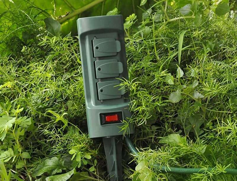 Vue rapprochée d'un piquet d'énergie verte planté dans le feuillage près d'un trottoir.