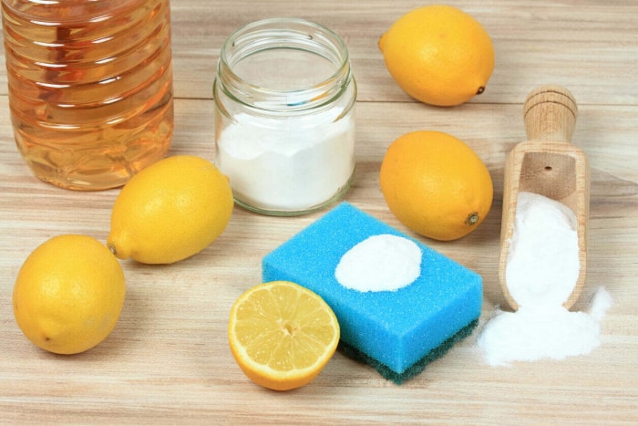 Citrons, sel, bicarbonate de soude et une éponge bleue sur du bois clair