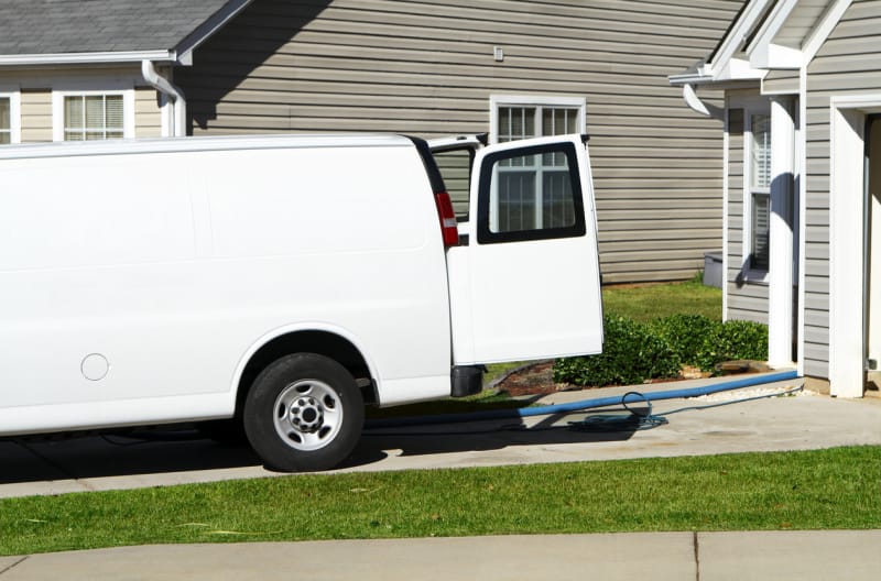 camionnette de travail blanche dans l'allée d'une maison de banlieue