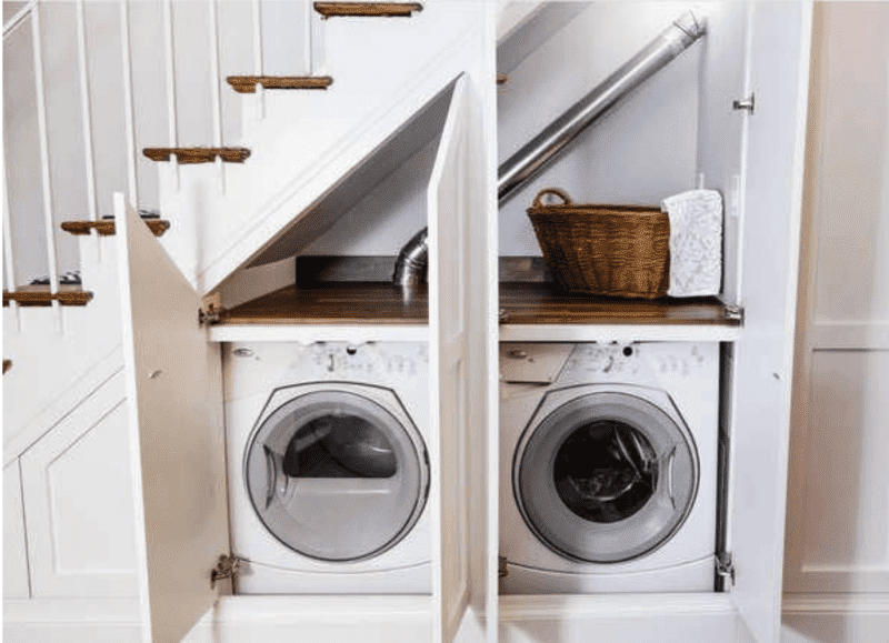 un lave-linge et un sèche-linge cachés sous un escalier dans un recoin avec deux portes ouvertes