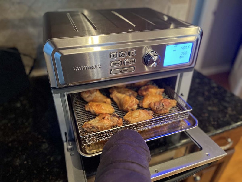 Personne retirant des ailes de poulet du four grille-pain Cuisinart air fryer