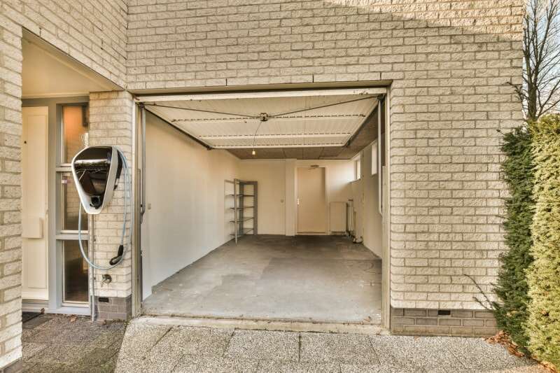 Maison en brique beige avec garage propre avec porte ouverte.