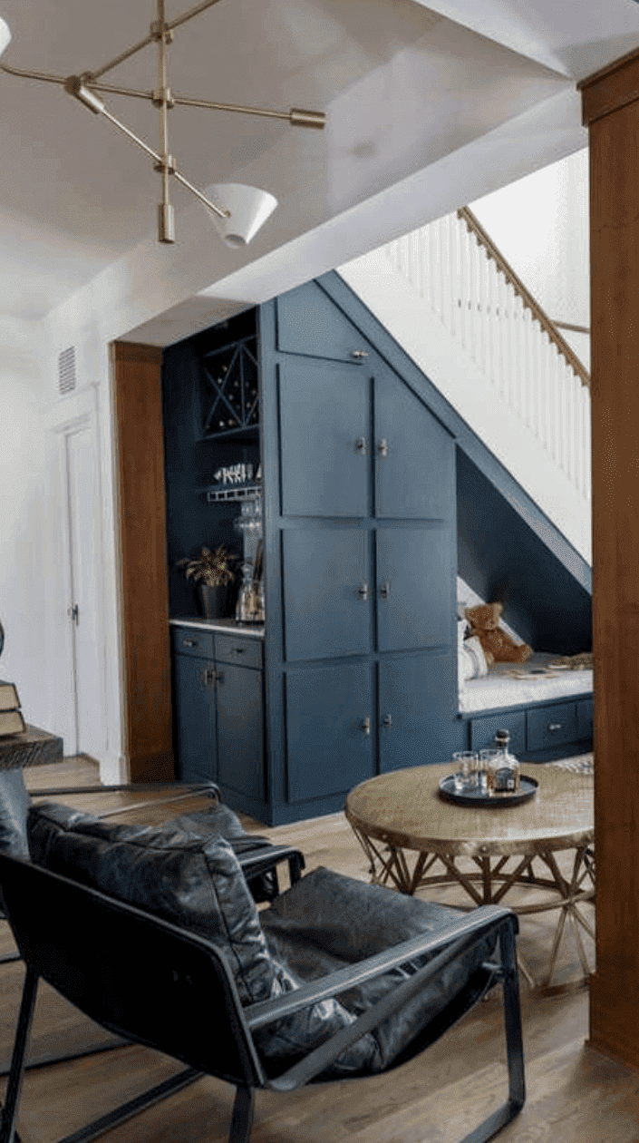 salon spacieux avec grandes armoires bleues et coin rangement sous l'escalier avec mini bar