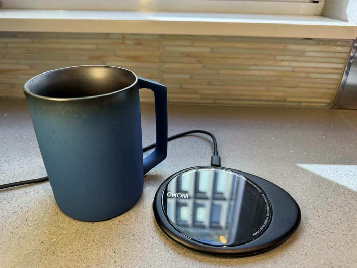 Une tasse auto-chauffante bleue de la collection Ohom Ui Artist à côté de son sous-verre chauffant sur un comptoir de cuisine avant le test.