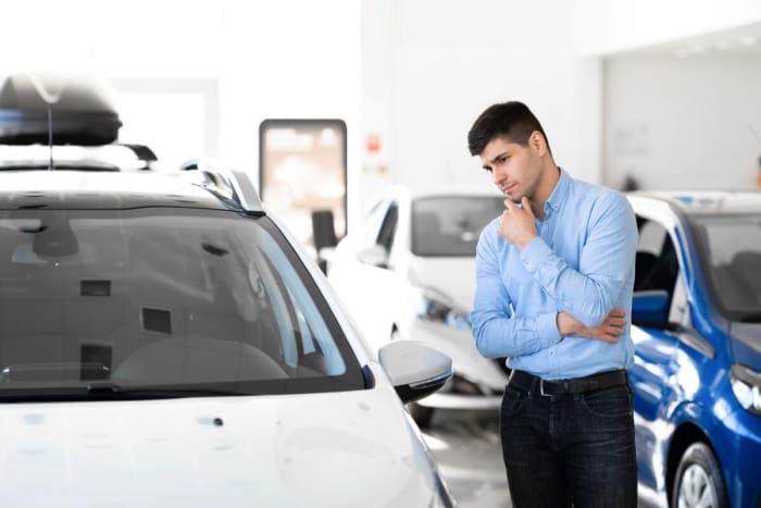 coûts cachés de la possession d'une voiture électrique - un homme envisage d'acheter une voiture