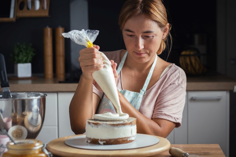 Une femme utilise un sac en plastique pour glacer un gâteau.