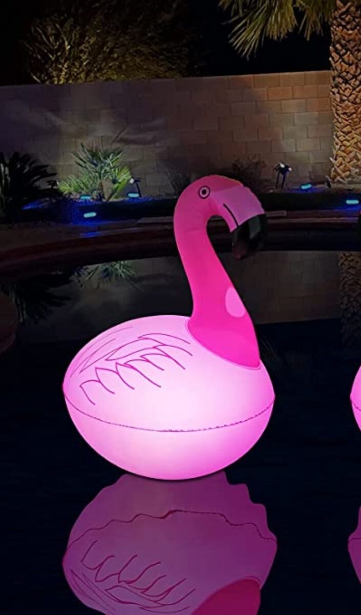 Une piscine la nuit est éclairée par des lumières de fête sur le thème des flamants roses.