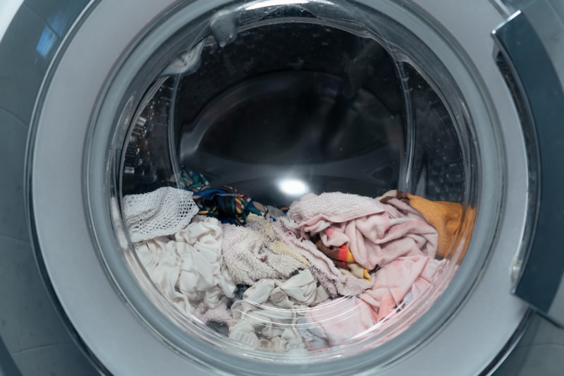 Un lave-linge à chargement frontal est rempli de linge mouillé.