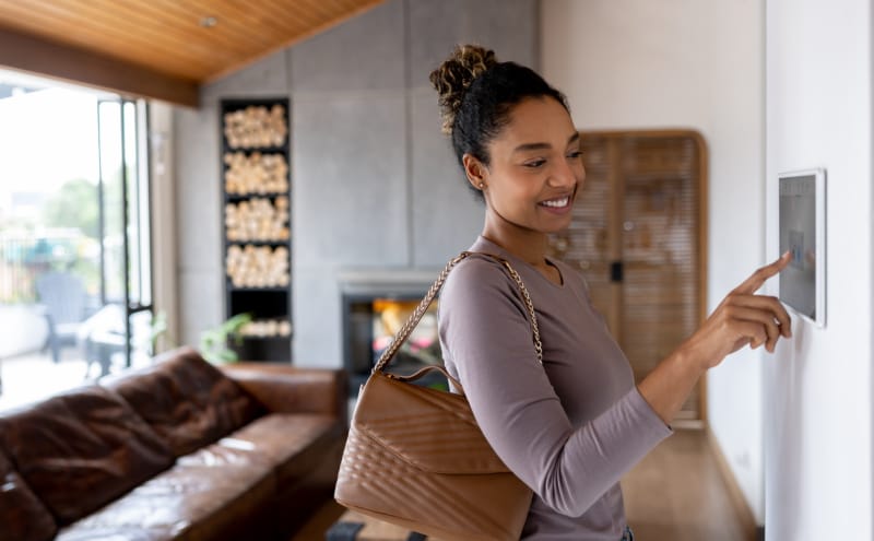 Une femme activant l'alarme en quittant sa maison intelligente à l'aide d'un système automatisé.