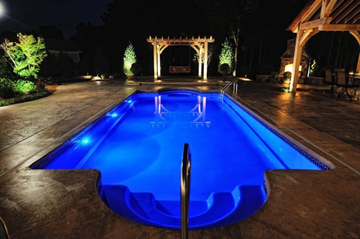 Piscine avec intérieur bleu et lumières pour baignade nocturne.