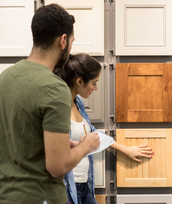 Un jeune couple examine des échantillons d'armoires dans un magasin de bricolage