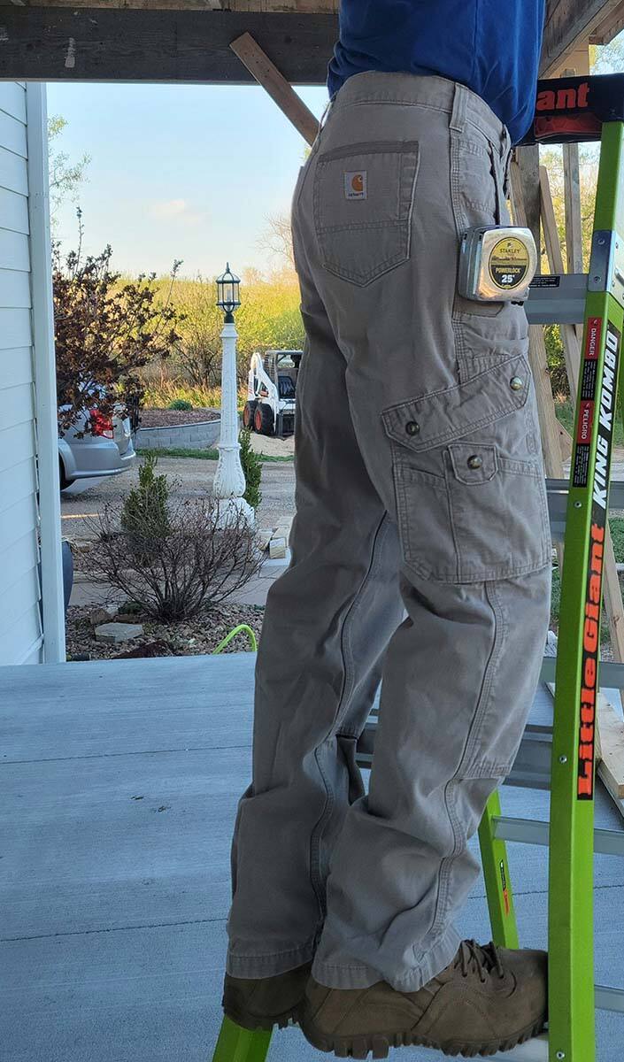 Homme en pantalon cargo Carhartt debout sur une échelle jaune