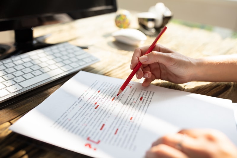 Gros plan de la main d'une personne marquant une erreur avec un marqueur rouge sur un document