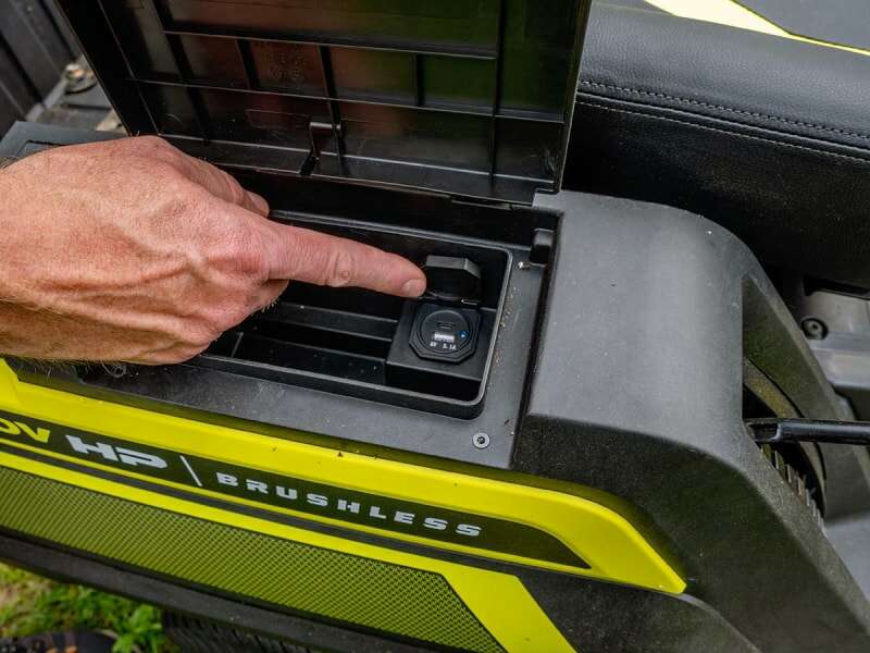 Main pointant vers les ports de charge de l'appareil sur le tracteur de pelouse électrique Ryobi