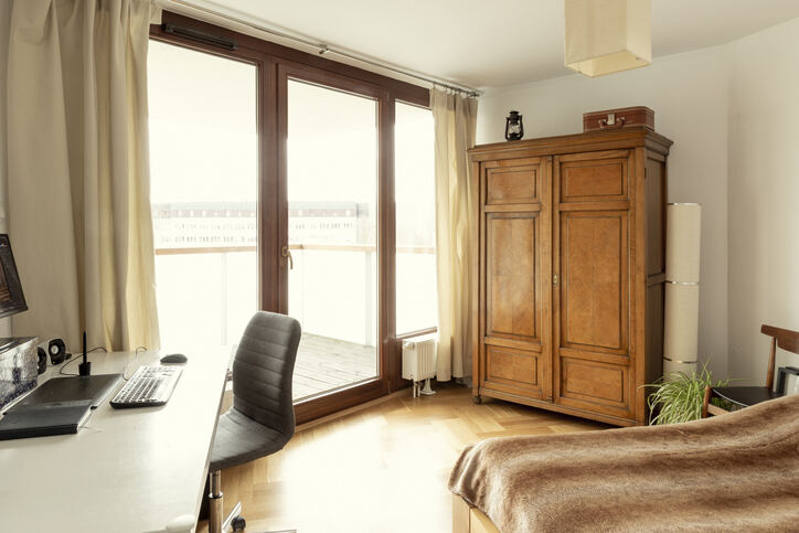 un appartement moderne avec bureau, lit et armoire en bois ainsi que des baies vitrées donnant sur un balcon